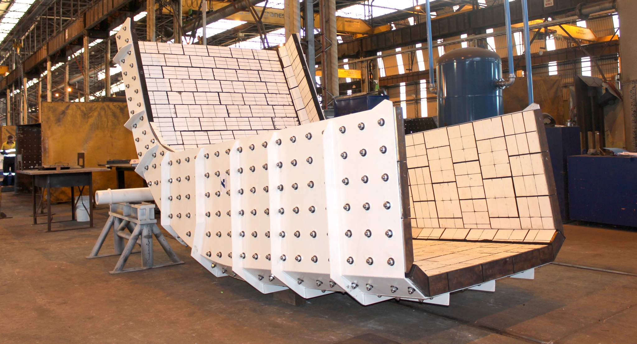 A segment of a white mining chute sitting in a workshop.