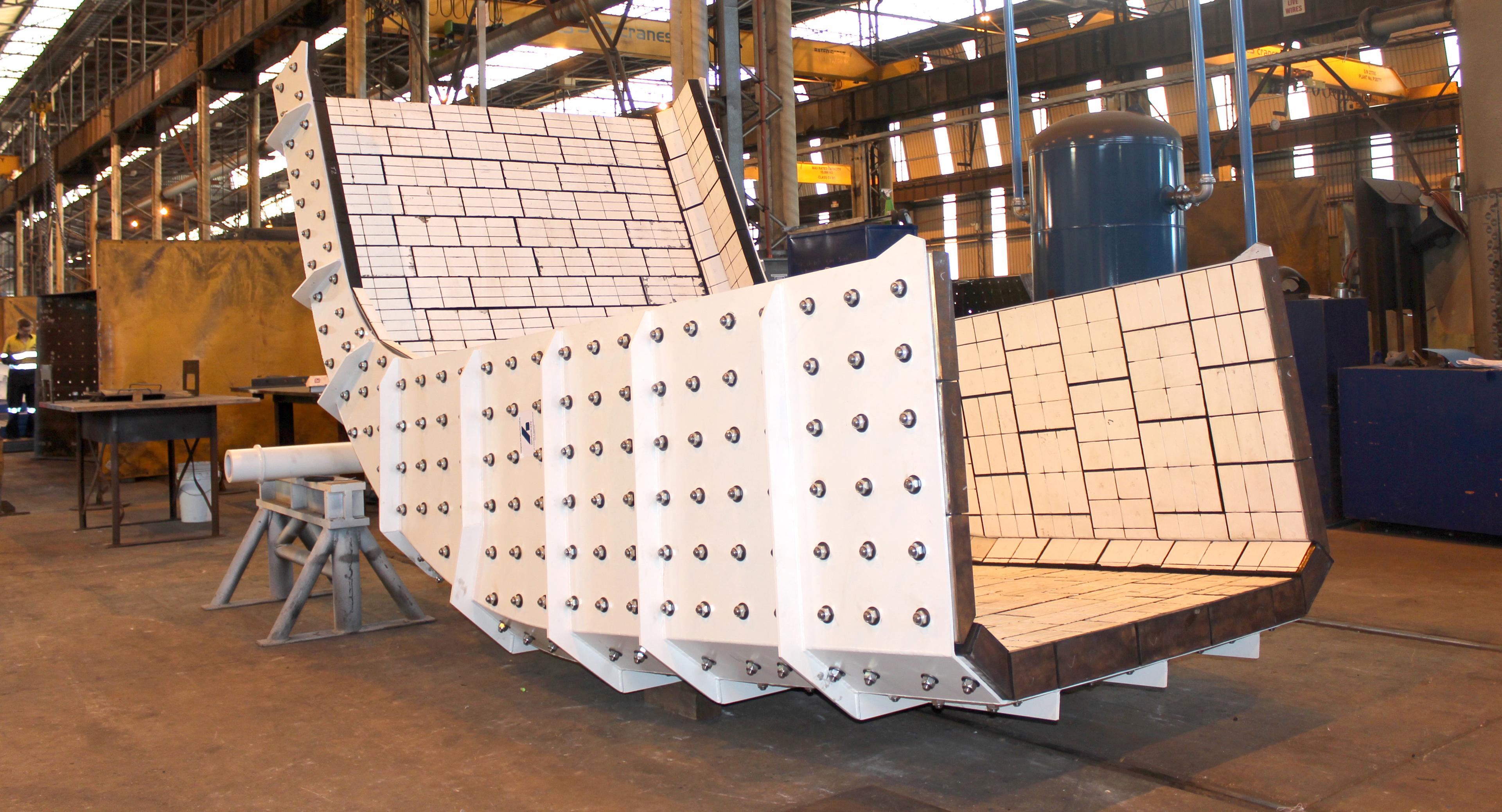 A segment of a white mining chute sitting in a workshop.